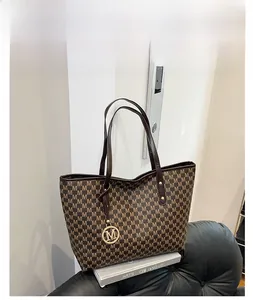 Macro shot of coffee brown tote bag with M-letter pattern and gold metal charm