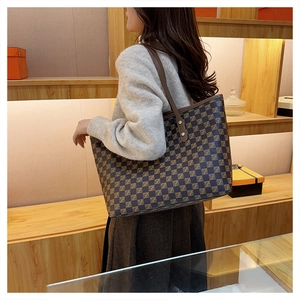 Detail view of large checkered tote bag with leather straps on a shoulder