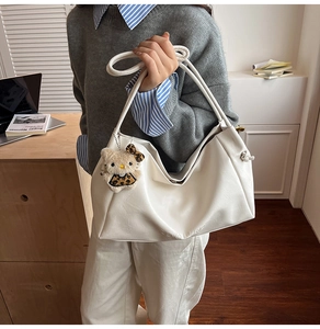 Close-up of white oversized hobo tote bag with Hello Kitty plush keychain and leather strap