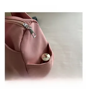 Detail of pink canvas tote bag showing metal zipper closure and side pocket texture