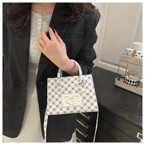 Detail of white leather shoulder bag with dark geometric pattern and embossed G logo plaque