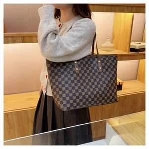 Close-up of checkered pattern tote bag with leather handles and gold rivet details