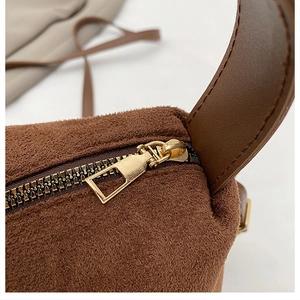 Detail einer braunen Wildleder-Handtasche mit hochwertigem goldfarbenem Reißverschluss