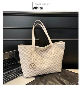 Detailed close-up of white tote bag with M-pattern print and gold charm on black leather