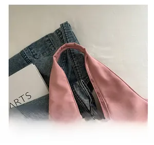Detail of soft pink tote bag with reinforced wide handles against denim and art book