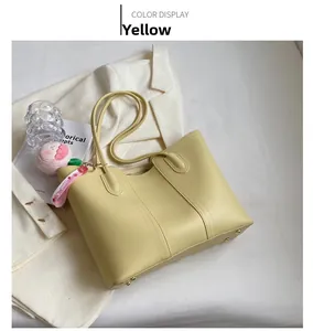 Detail of yellow leather tote bag with a plush charm accessory on a white background