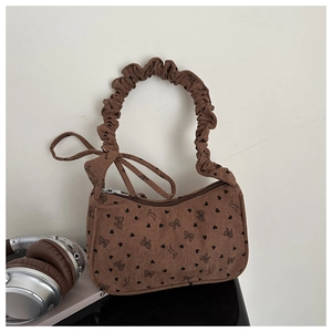 Detail of brown corduroy saddle bag with heart patterns and pleated handle knots