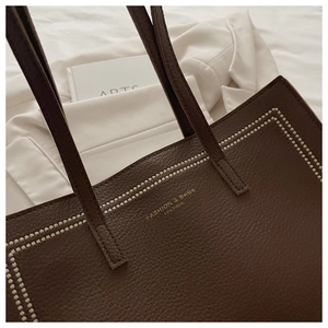 Détail du sac cabas en cuir marron foncé avec bordure perlée blanche et lettrage doré