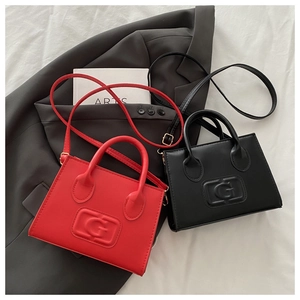 Detail view of red and black square handbags with embossed G logo on white fabric