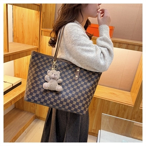Detailed side view of checkered tote bag with a cute plush bear charm on the strap