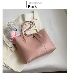 Pink faux leather tote bag with protective gold feet and cute doll pendant on fabric