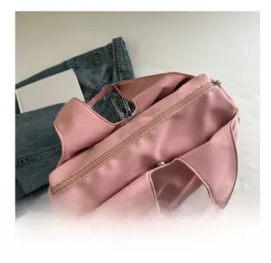 Detail view of pink pleated nylon tote bag with top zipper and wide shoulder straps