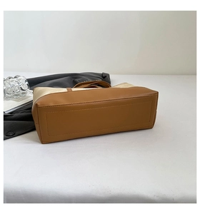 Detail view of the rectangular leather base and reinforced stitching of a tote bag