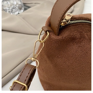 Details einer braunen Wildledertasche mit goldenem Reißverschluss und Lederriemen-Textur