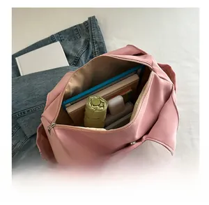 Detail view of pink pleated shoulder bag interior showing large capacity for laptop and umbrella