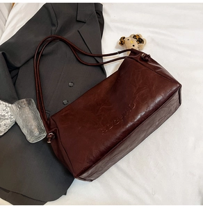 Detailed close-up of dark brown tote bag with embossed RDCHAD lettering and long straps