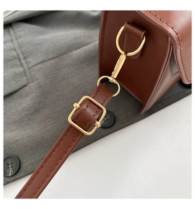 Detail view of dark brown leather strap with golden metal hardware and stitching