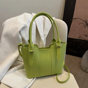 Elegant bright green PU leather bucket tote bag with crossbody strap on a white chair