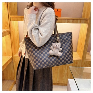 Detail showing checkered tote bag with Z pattern and a cute plush bear charm accessory