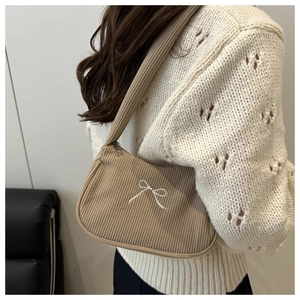 Close-up of light brown corduroy underarm bag featuring delicate white bow embroidery