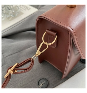 Detailed macro shot of golden metal hardware and d-ring on brown pebble leather handbag