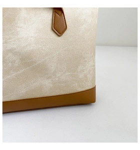 Close-up of beige large-capacity tote bag with brown leather trim and contrast stitching