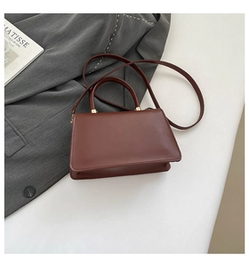 Detail of dark brown leather handbag with cylindrical handle and gold hardware accents