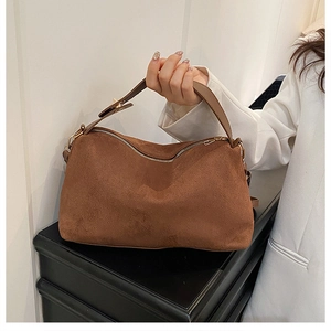 Close-up of a brown suede half-moon hobo bag with elegant gold metal hardware and zipper