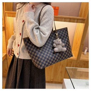 French style brown checkerboard tote bag with cute bear charm worn by a model