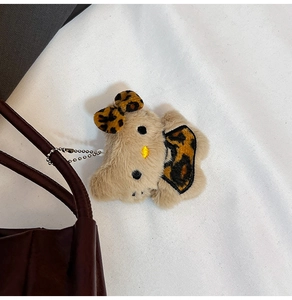 Detail of Hello Kitty plush keychain with leopard bow and silver chain on brown bag