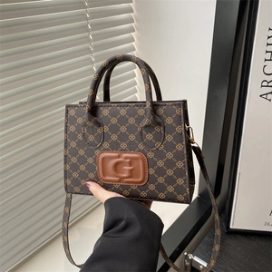 Chic monogram crossbody bag with G logo embossing and leather handles in dark brown