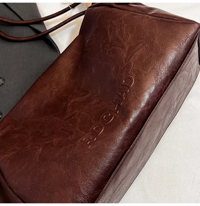 Close-up of dark brown tote bag showing retro wrinkled leather texture and embossed logo