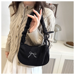 Detail of black corduroy bag featuring white bow embroidery and ruffled handle design