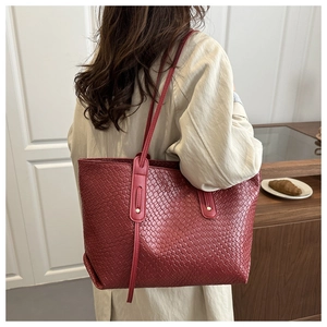 Detailed view of red woven leather tote bag with a high-gloss finish and dual straps