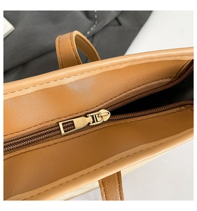 Detailed close-up of premium gold zipper and textured brown leather on large tote bag