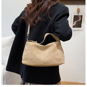 Detail der beigen Wildleder-Hobo-Tasche mit goldenen Beschlägen und Schultergurten