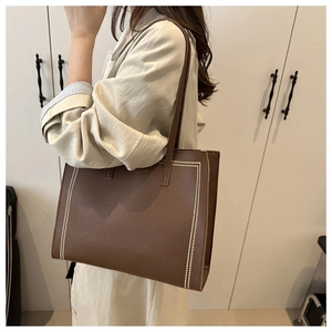 Gros plan sur le sac fourre-tout en cuir litchi marron avec surpiqûres blanches
