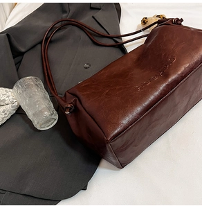 Detail of dark brown vintage leather tote with RIDGI-MAND embossing and knotted strap
