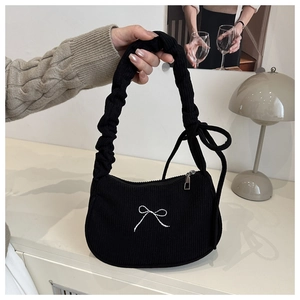 Detail of black corduroy handbag featuring white bow embroidery and ruffled handle