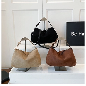 Three vintage matte handbags in black, beige, and brown on a tiered metal stand