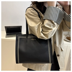 Détail d'un grand sac cabas noir avec rivets dorés et texture cuir pour les déplacements pro