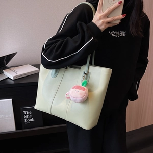 Mint green minimalist tote bag with plush charm shown in a casual lifestyle setting