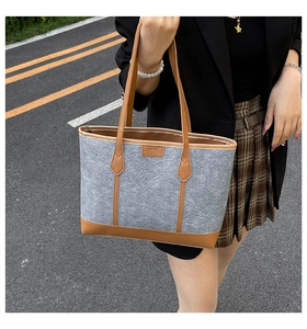 Close-up of a large grey felt tote bag with brown leather handles for daily commute