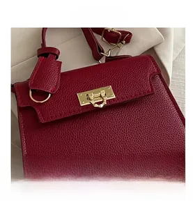 Detail einer dunkelroten Handtasche aus Leder mit goldener rechteckiger Metallschließe