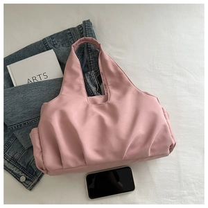 Pink pleated tote bag in durable nylon shown with lifestyle props and a blue denim jacket