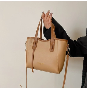 Close-up of beige leather bucket bag featuring gold hardware and detachable shoulder strap