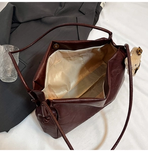 Detail view of large dark brown leather tote bag with magnetic closure and bear charm