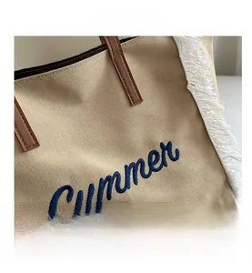 Détail de la broderie Summer bleue sur le sac en toile avec franges et poignée en cuir
