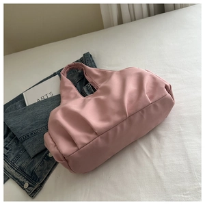 Detail of pink pleated shoulder bag with smooth fabric texture on white bedding