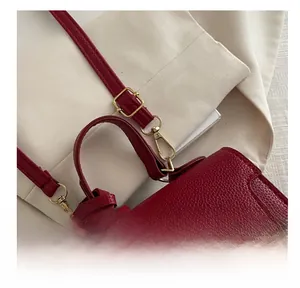 Detail der verstellbaren Schnalle an der weinroten Lederhandtasche mit goldener Hardware
